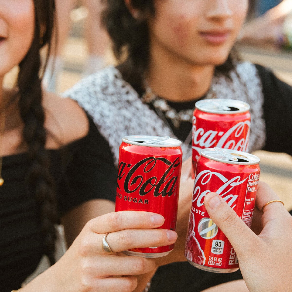 Closeup of friends holding Coca-Cola cans