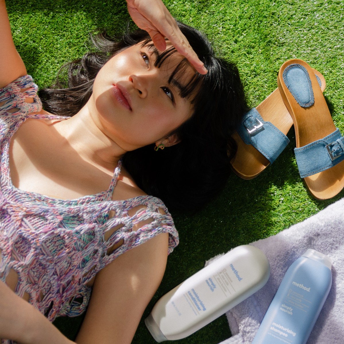 Coachella fan laying grass with method products next to her