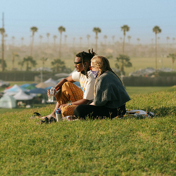 Two Coachella fans sitting on grass